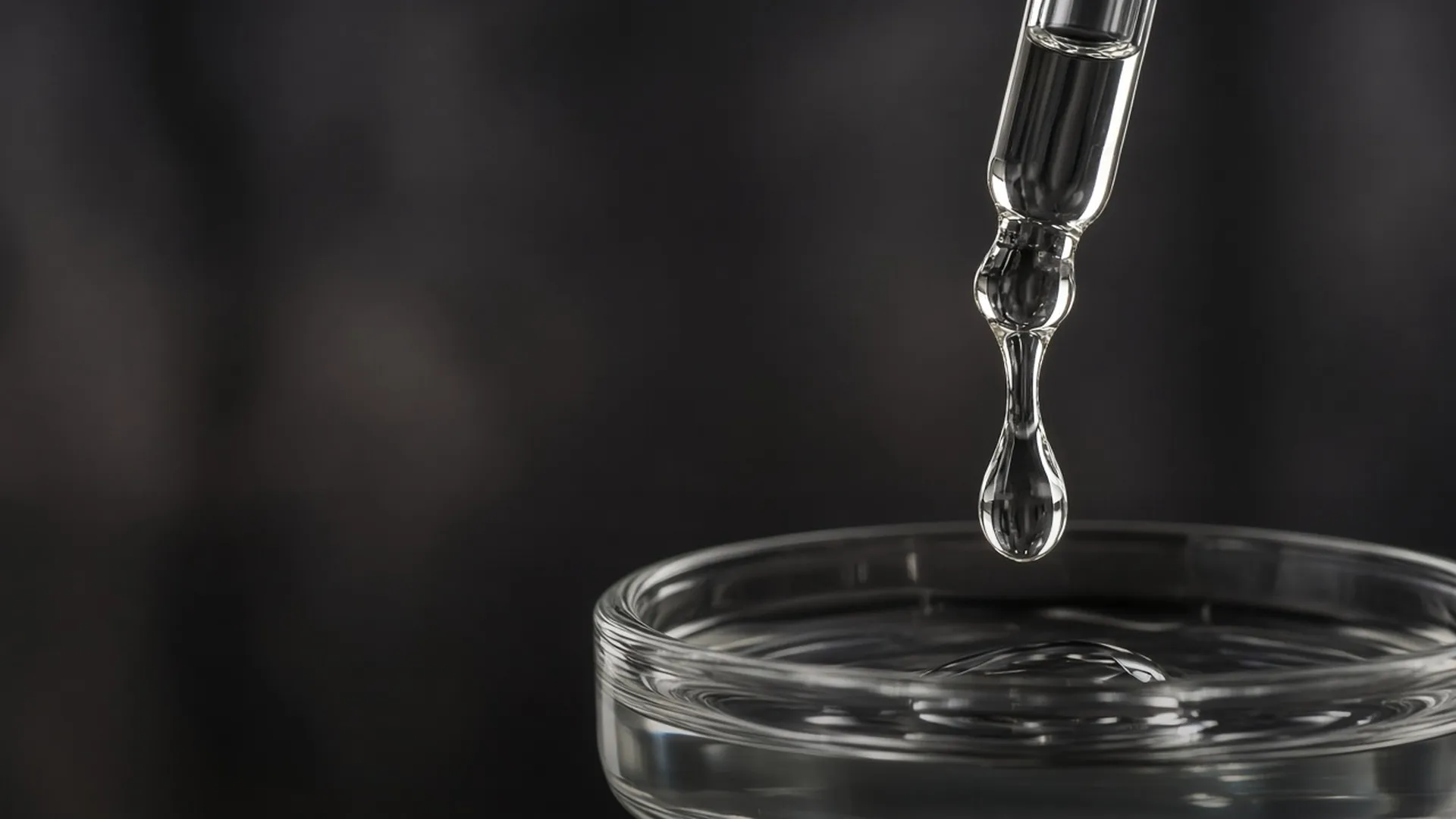 A glass dropper releasing a drop of clear gel